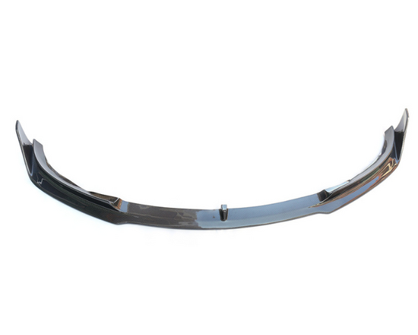 A black carbon fiber car front lip spoiler rests on a plain white background, showcasing its sleek, aerodynamic design with raised ends and slight curvature.