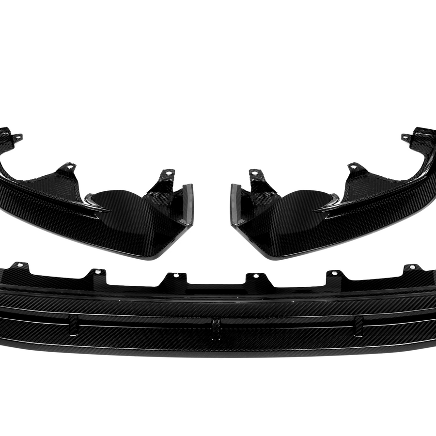 Carbon fiber car parts, including two curved side panels and a central diffuser, displayed against a white background. The pieces have a glossy finish and intricate texture.
