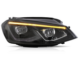 A sleek car headlight with dual LED projectors and an amber LED strip is illuminated against a plain white background, highlighting its modern design.