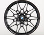 A black, multi-spoke alloy wheel displays a BMW logo at the center, set against a plain white background, highlighting its intricate design.