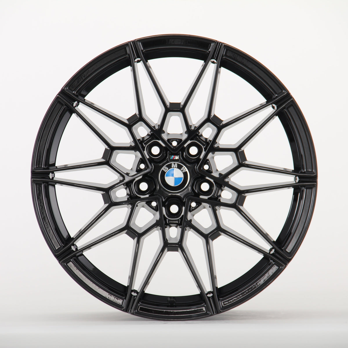 A black, multi-spoke alloy wheel displays a BMW logo at the center, set against a plain white background, highlighting its intricate design.