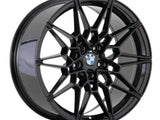 A black alloy wheel features a complex, geometric spoke design centered by a BMW logo, displayed against a plain white background.