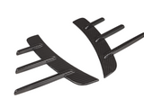 Carbon fiber car parts lie side by side, showcasing aerodynamic fin designs on a white background, highlighting their sleek and modern appearance.