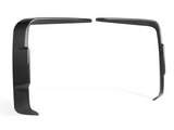Two black carbon fiber trim pieces are positioned in a parallel arrangement, standing upright. They are slightly bent and set against a plain white background.