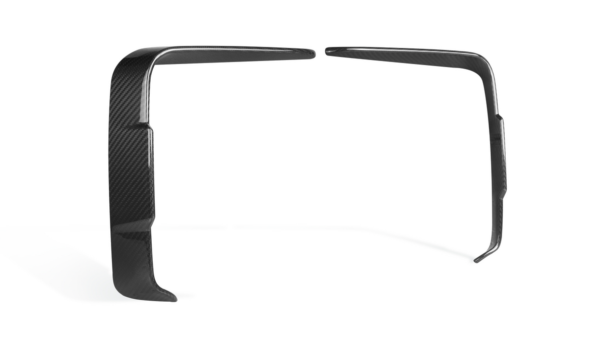Two black carbon fiber trim pieces are positioned in a parallel arrangement, standing upright. They are slightly bent and set against a plain white background.