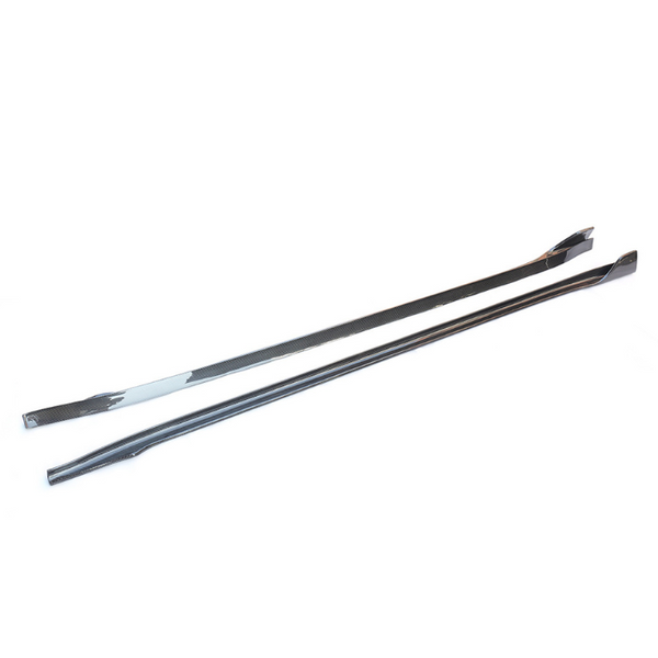 Two long, sleek carbon fiber strips with a glossy finish lie parallel on a plain white surface. Their ends taper slightly, and they have a consistent dark weave pattern.