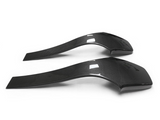 Two curved carbon fiber car spoilers rest side by side on a plain white background, exhibiting sleek, aerodynamic shapes with a glossy finish and subtle texture lines.
