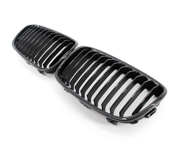 A pair of black, glossy car grilles featuring vertical slats, positioned side by side on a plain white background.