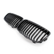 A pair of black, glossy car grilles featuring vertical slats, positioned side by side on a plain white background.