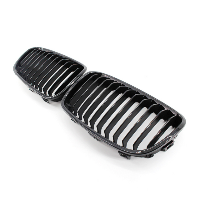 A pair of black, glossy car grilles featuring vertical slats, positioned side by side on a plain white background.