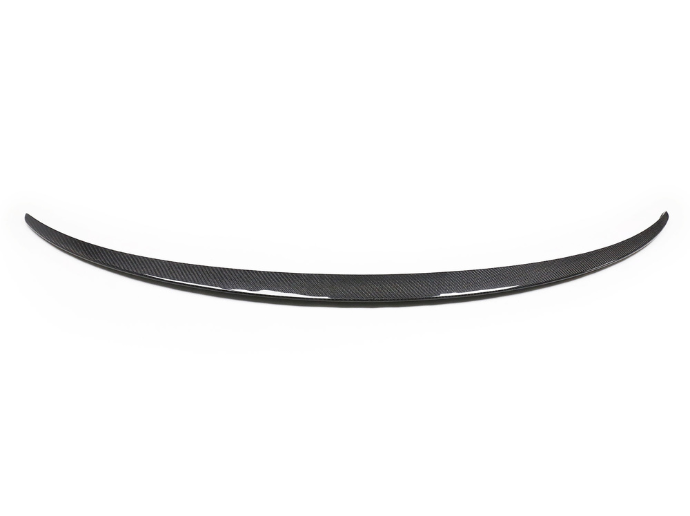 A curved carbon fiber car spoiler lies against a plain white background, showcasing its aerodynamic design and glossy texture.