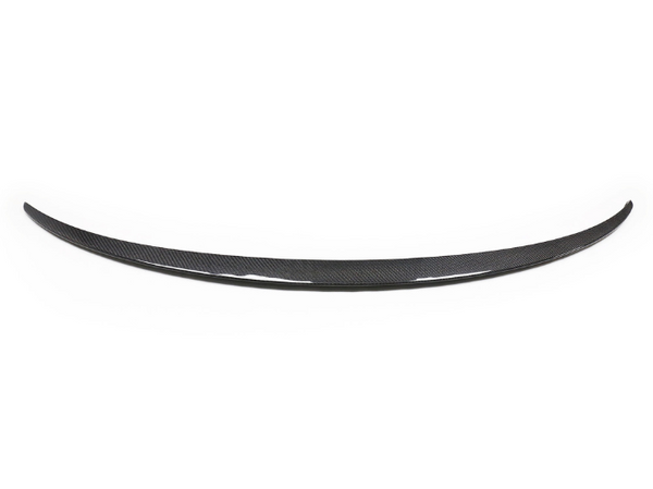 A curved carbon fiber car spoiler lies against a plain white background, showcasing its aerodynamic design and glossy texture.