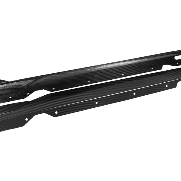 Two black carbon fiber car side skirts lie parallel, featuring aerodynamic fins and multiple mounting holes, against a plain white background.