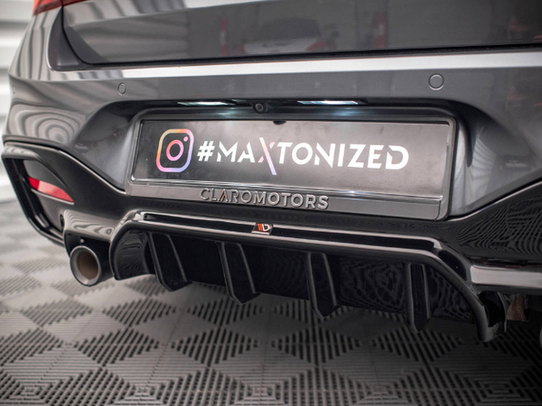 A car's rear with a diffuser and visible exhaust pipe. License plate reads “#MAXTONIZED CLARO MOTORS,” and Instagram logo. Background features a patterned floor, suggesting an indoor showroom.