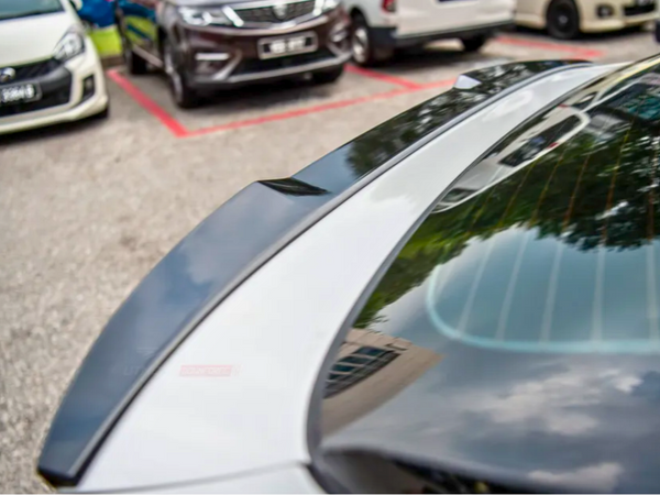 A car with a reflective rear windshield shows tree and building reflections, parked in a lot among other vehicles, delineated by red lines.