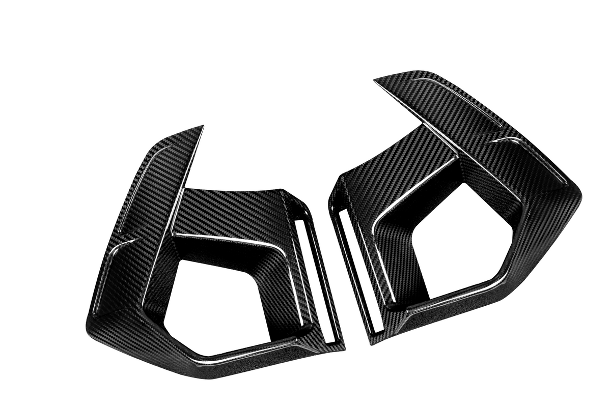 Two black carbon fiber car parts, shaped with angular edges, rest against a white background. They appear to be side mirrors or aerodynamic components.