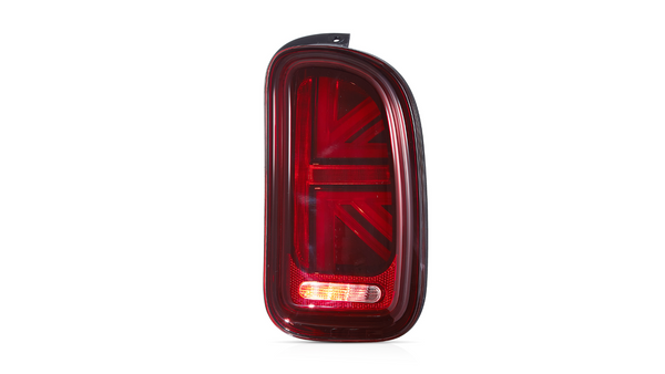 A red car taillight features a stylized Union Jack design. It is illuminated against a plain white background, showcasing its detailed pattern and glossy surface.