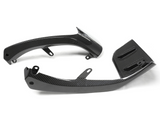 Two carbon fiber motorcycle components lie on a plain white background. The parts feature sleek curves and attachment points, suggesting they are used for structural or aerodynamic enhancements.