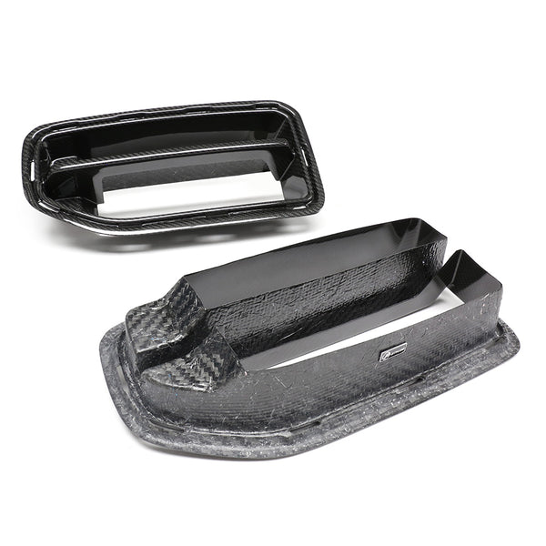 Rectangular carbon fiber car air vents resting on a white background. The vents feature a sleek, shiny finish with a layered design, highlighting their aerodynamic appearance.