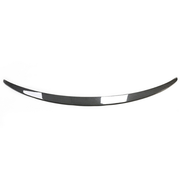 A curved carbon fiber car spoiler lies flat against a plain white background, highlighting its sleek design and lightweight material.