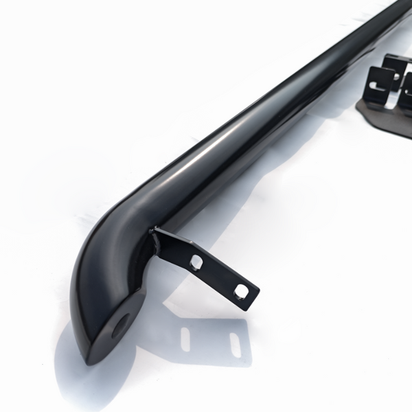 A black metal bar with mounting brackets is positioned on a plain white surface, likely part of a vehicle accessory or structural component.