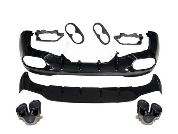 A disassembled car body kit includes a black front bumper with vent openings, a lower splitter, light bezels, and dual exhaust tips, arranged on a plain white background.