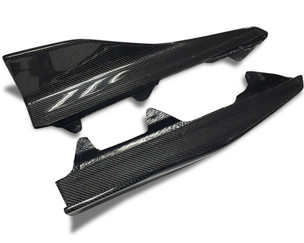 Two carbon fiber car side skirts resting on a white surface. The top piece features a stylized “TT” logo, enhancing its sleek, modern appearance.