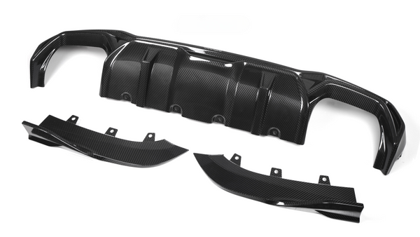 Carbon fiber car diffuser components lie on a white background. The main piece, with multiple ridges, is accompanied by two curved side parts, each featuring mounting brackets.