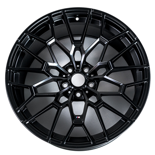 Wheel with intricate black spoke design features "M" logo at center, resting against a plain white background.