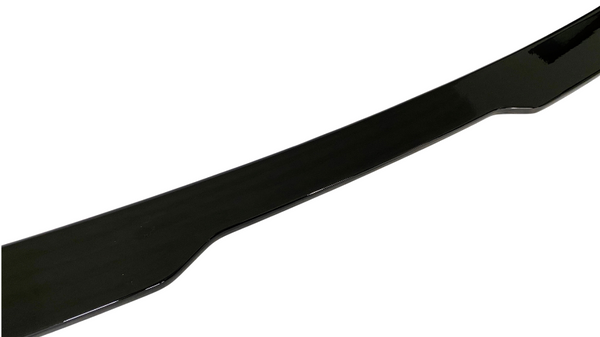 A glossy black car spoiler lies slightly curved against a white background, showing its aerodynamic form intended for enhanced vehicle performance.
