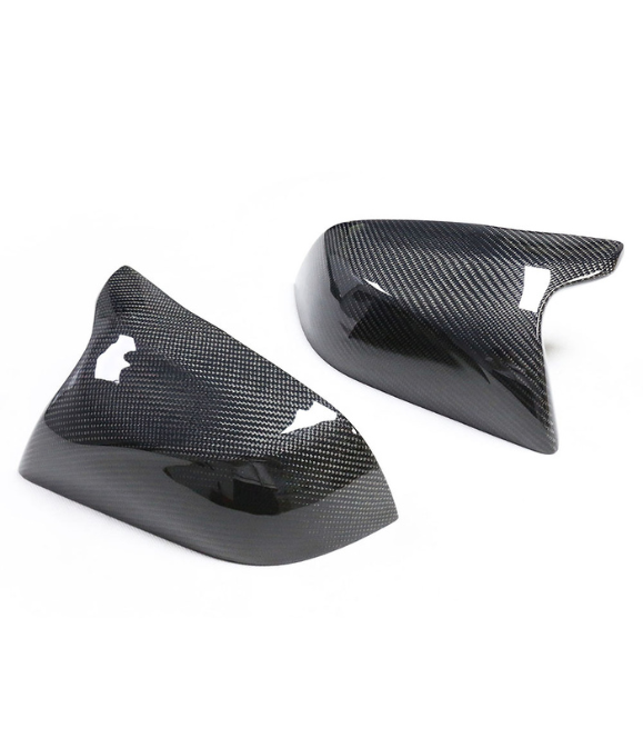 Two carbon fiber car mirror covers lie on a plain white surface, displaying a sleek, glossy finish with a distinct woven pattern.