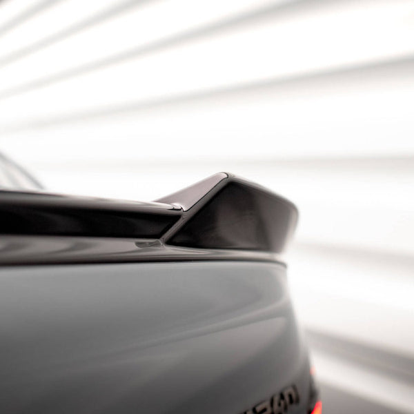 A car rear spoiler is positioned diagonally, set in a blurred, bright background with horizontal lines, suggesting a dynamic, modern environment.