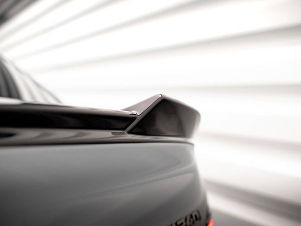 A car rear spoiler is positioned diagonally, set in a blurred, bright background with horizontal lines, suggesting a dynamic, modern environment.