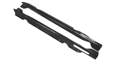 Two black carbon fiber side skirts are displayed, angled slightly apart, on a plain white background. The texture shows a diagonal weave pattern with small mounting holes along their length.