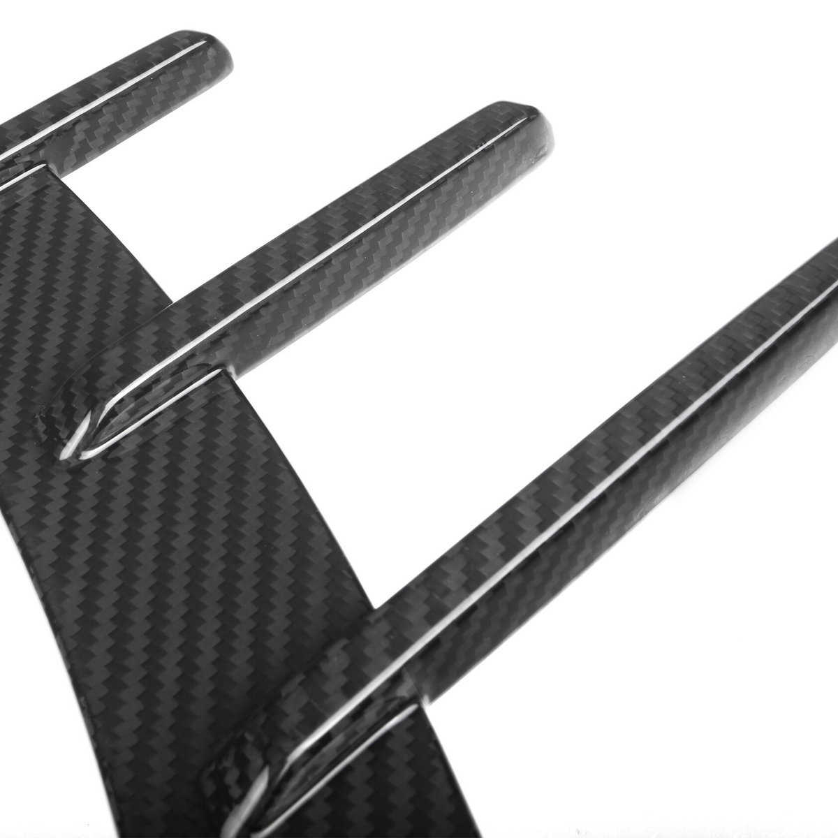 A carbon fiber diffuser with three vertical fins extends outward, angled against a plain white background, showcasing its sleek, aerodynamic design.