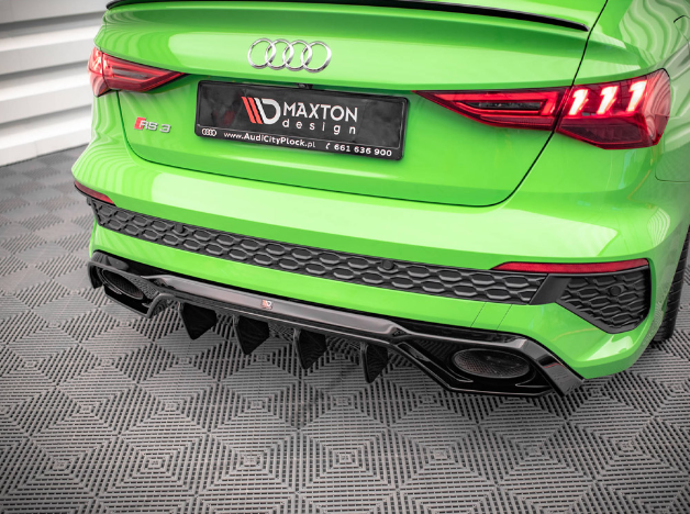 A green Audi RS 3 displays a Maxton Design license plate. The car is parked on a patterned floor indoors. The license plate reads: "MAXTON design www.AudiCityPlock.pl 661 636 900".