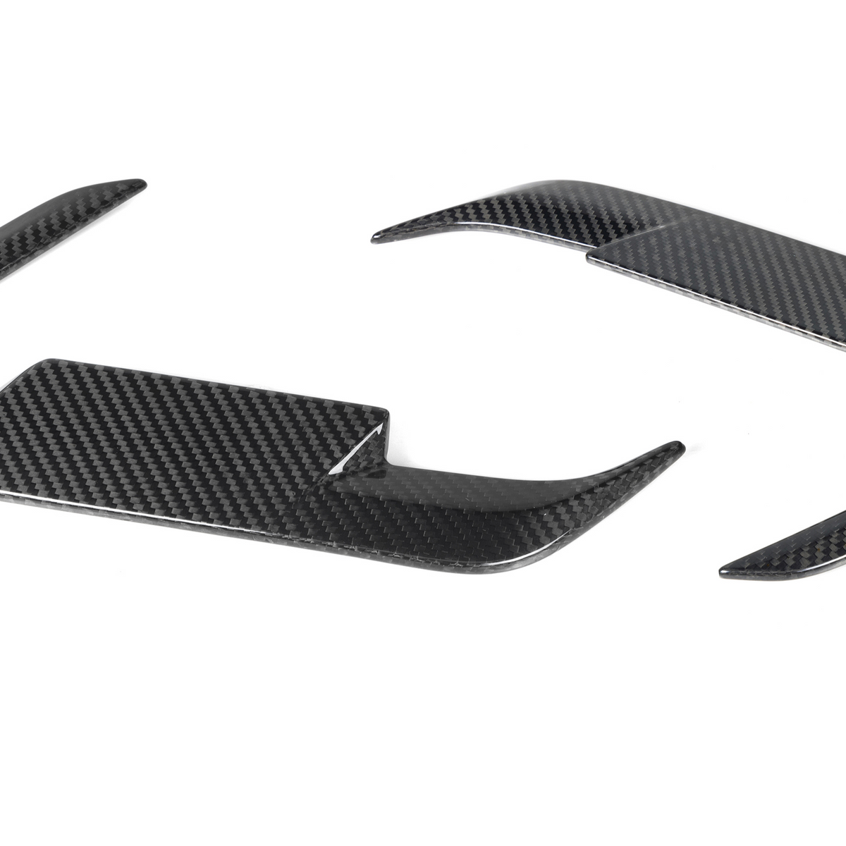 Carbon fiber steering wheel trim pieces, curved and glossy, rest on a plain white background.