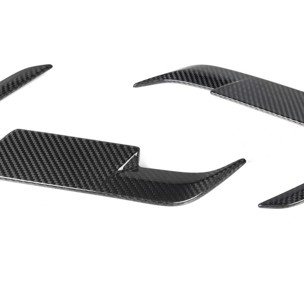 Carbon fiber steering wheel trim pieces, curved and glossy, rest on a plain white background.