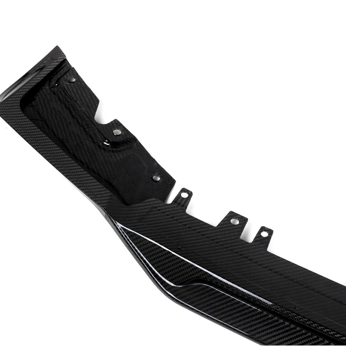 A black carbon fiber automotive component, featuring mounting points and textured patterns, lies against a plain white background.