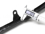A digital caliper measures a black carbon fiber object labeled 