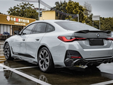 A silver car is parked on a wet pavement near a restaurant with illuminated signage in Chinese characters and telephone numbers: 