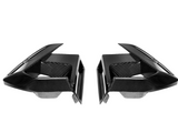 Two symmetrical, black carbon fiber air vents with sharp angles, facing each other, against a plain white background.