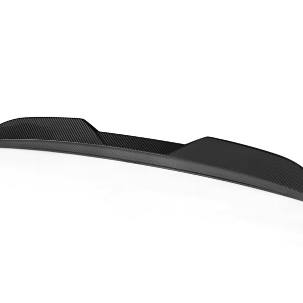 A black carbon fiber car spoiler rests on a plain white background, showcasing a sleek, aerodynamic design with subtle curved contours and a textured finish.