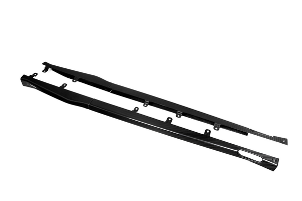 Two long, black carbon fiber side skirts lie flat with mounting brackets, displayed against a plain white background.