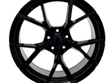 A black, multi-spoke alloy wheel is shown, featuring a sleek, glossy finish and a circular design with five lugs, isolated against a white background.