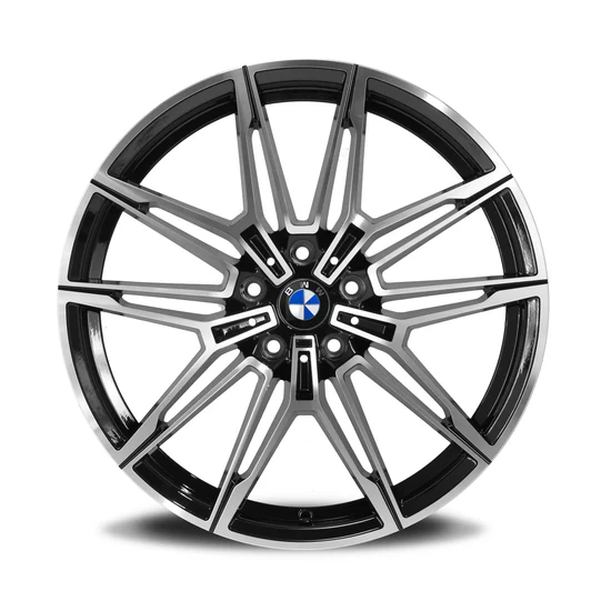 A polished, multi-spoke car wheel rim with a central BMW logo rests against a white background. The design features intricate, symmetrical patterns with alternating black and metallic finishes.