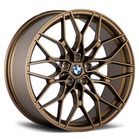 A bronze alloy wheel with intricate spoke design displays the BMW logo at its center, set against a plain white background.