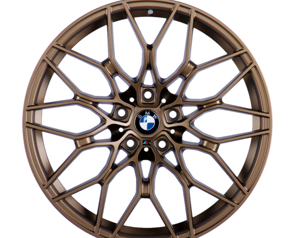 Bronze car wheel with intricate, multi-spoke design, centered on a logo featuring black, white, and blue colors, resting against a plain white background.