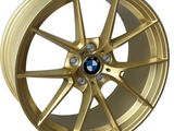 A gold alloy wheel, featuring a five-spoke design, displays a BMW emblem at the center. Raised text near the rim edge reads 