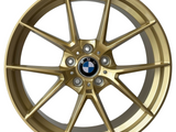 A gold alloy wheel with a black and white BMW logo at the center. The rim is marked 